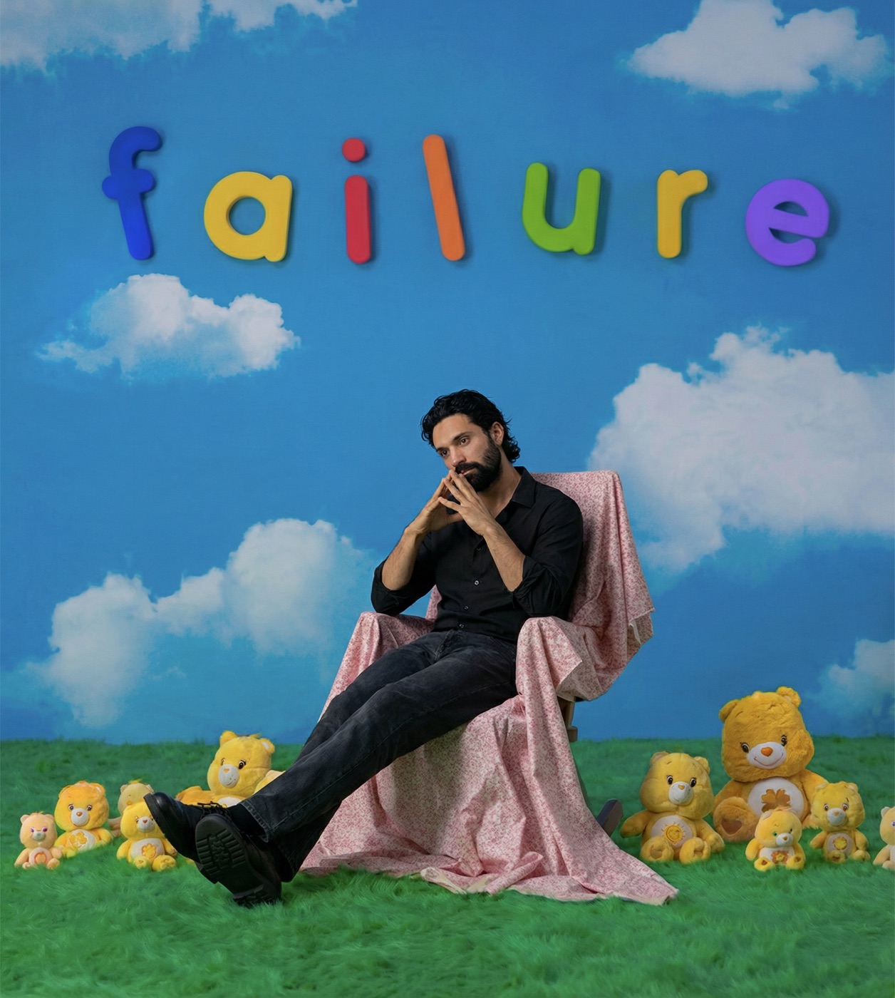 Amos Le Blanc seated among Care Bear toys below colorful letters spelling failure