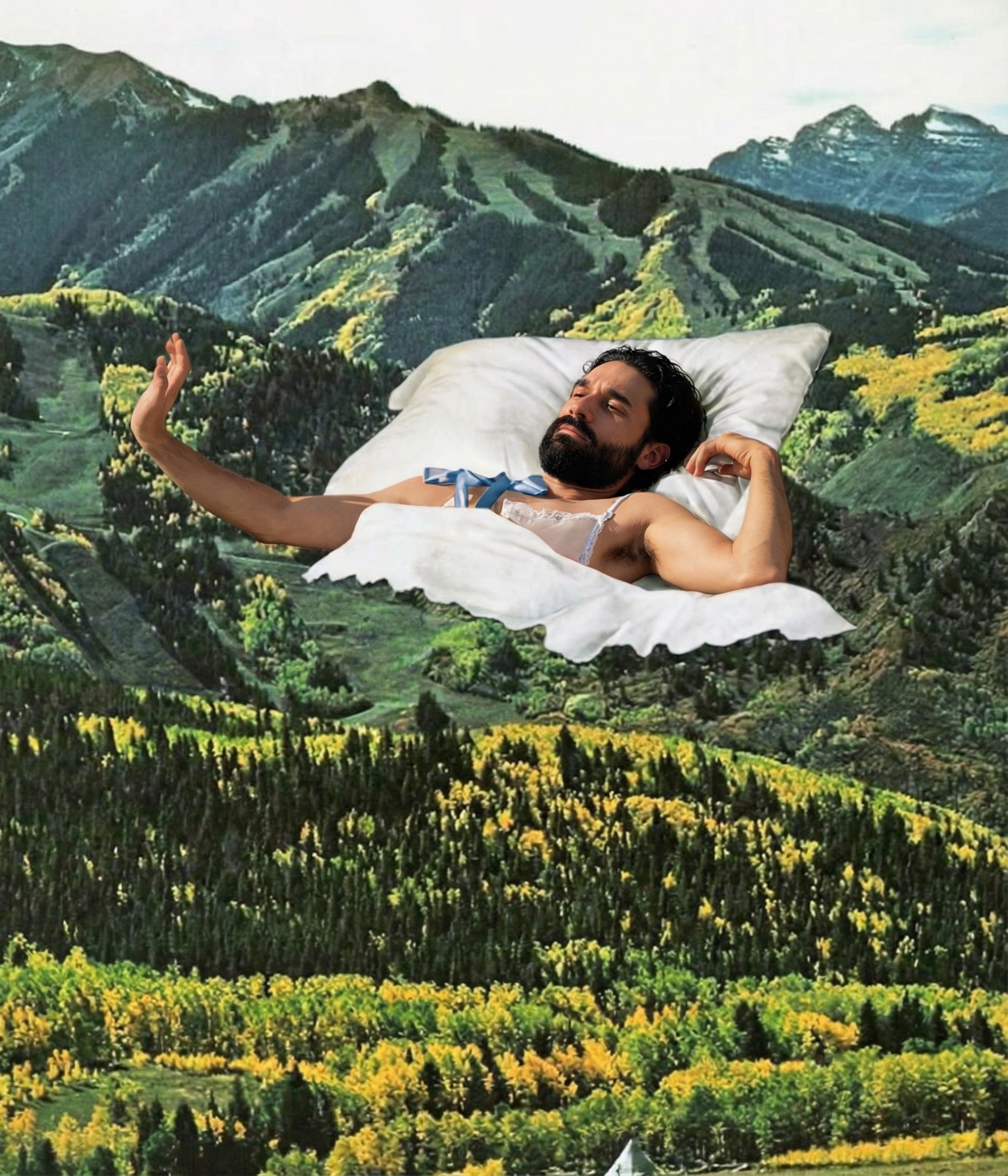 Amos Le Blanc reclining on a pillow in a white lace top against a mountain forest scene